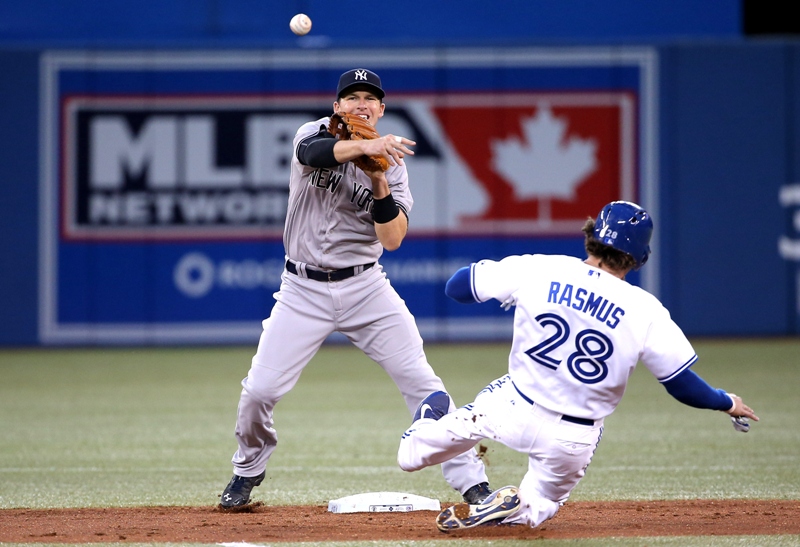 Stephen Drew #33 of the New York Yankees turns the double play in the third inning during MLB game action as Colby Rasmus #28 of the Toronto Blue Jays slides into second base on August 29, 2014 at Rogers Centre in Toronto, Ontario, Canada. (Photo by Tom Szczerbowski/Getty Images).