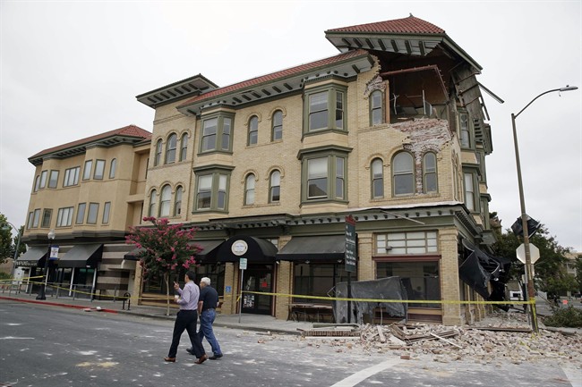 Two men walk past the earthquake-damaged building that housed the Carpe Diem wine bar Monday, Aug. 25, 2014, in Napa, Calif. The San Francisco Bay Area's strongest earthquake in 25 years struck the heart of California's wine country early Sunday, igniting gas-fed fires, damaging some of the region's famed wineries and historic buildings, and sending dozens of people to hospitals. (AP Photo/Eric Risberg).