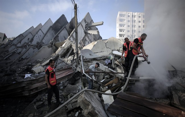 In this Tuesday, Aug. 26, 2014 file photo, Palestinian firefighters extinguish a fire in the rubble of the destroyed 15-story Basha Tower, following early morning Israeli airstrikes in Gaza City. 