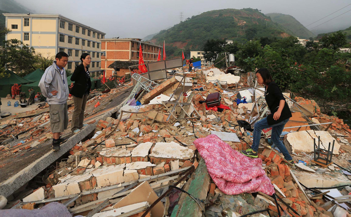 In this photo provided by China's Xinhua News Agency, teachers search for their belongings from the collapsed dormitories at Longquan Middle School in Longtoushan town of Ludian county, southwest China's Yunnan Province, Tuesday, Aug. 5, 2014. 