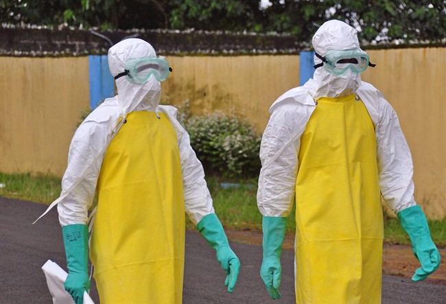 Health workers wearing protective gear go to remove the body of a person who is believed to have died after contracting the Ebola virus in the city of Monrovia, Liberia, Saturday, Aug. 16, 2014. 