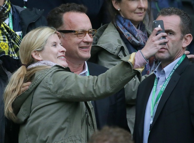 In this picture taken Saturday May 17, 2014, US actor Tom Hanks, second left, and a young woman take a photo during the German soccer cup final between Bayern Munich and Borussia Dortmund at the stadium in Berlin.  THE CANADIAN PRESS/ AP, dpa, Kay Nietfeld.