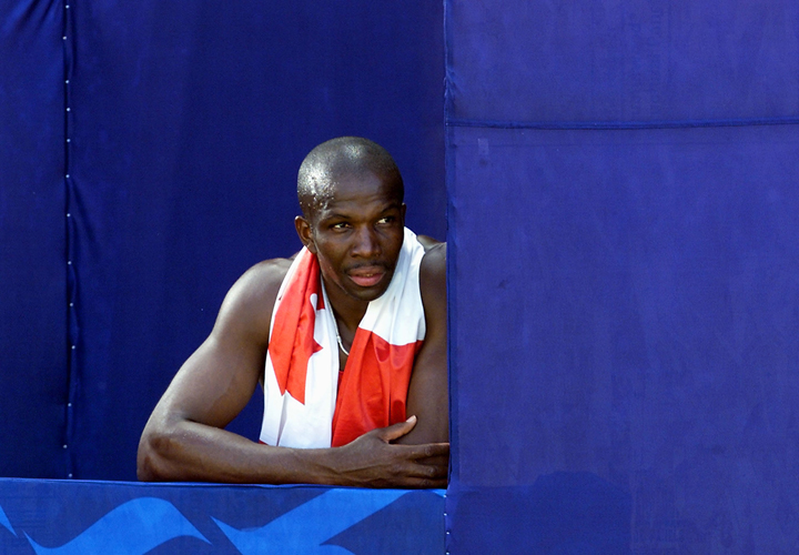 Donovan Bailey looks out at the track from behind the signboards after failing to qualify for the final of the men's 100M at the 8th World Championships in Athletics 05 August 2001 at the Commonwealth Stadium in Edmonton. 