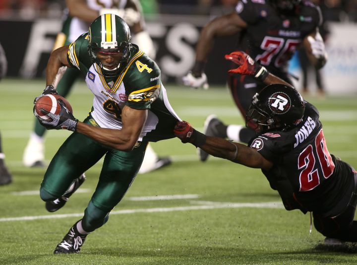 Reggie Jones #20 of the Ottawa Redblacks grabs at the jersey of Adarius Bowman #4 of the Edmonton Eskimos for a tackle after a catch during a CFL game at TD Place Stadium on August 15, 2014 in Ottawa, Ontario, Canada. 