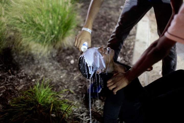 A woman has her face doused with milk after being tear gassed by police as she was protesting Michael Brown’s murder August 17, 2014 in Ferguson, Missouri.