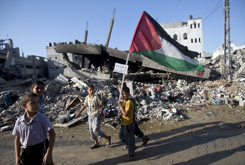 A group of Palestinian boys walk past destroyed houses in the Shejaiya neighbourhood of Gaza City on August 27, 2014, following the long-term truce agreed between Israel and the Palestinians.
