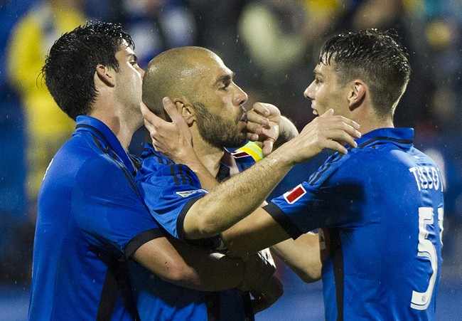 Montreal Impact's Marco Di Vaio, centre, celebrates with teammates Eric Miller, left, and Maxim Tissot after scoring against the Chicago Fire during second half MLS soccer action in Montreal, Saturday, August 16, 2014.