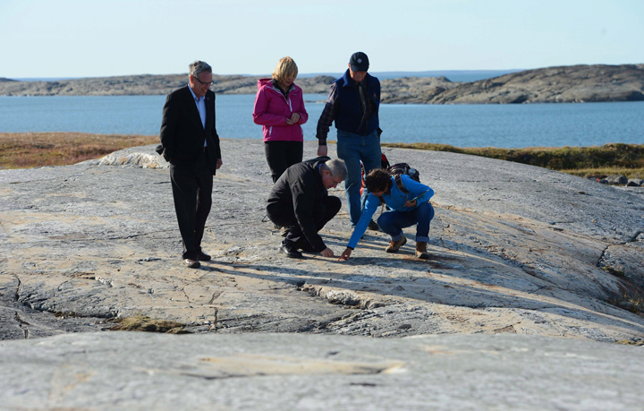Prime Minister Stephen Harper points to a rock as he is given a geological tour by Director General at the Geological Survey of Canada Donna Kirkwood, bottom right, and retired Geological Survey of Canada scientist Dr. Denis St-Onge, right, along with wife Laureen Harper, middle, and Minister of Natural Resources Joe Oliver, left, in Rankin Inlet, Nunavut on Thursday, August 22, 2013.
