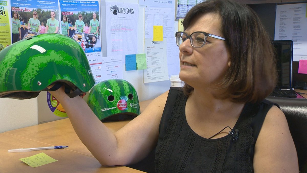 Glenda James, executive director of the Saskatchewan Brain Injury Association, holds up one of the watermelon-themed helmets being given out for the campaign.