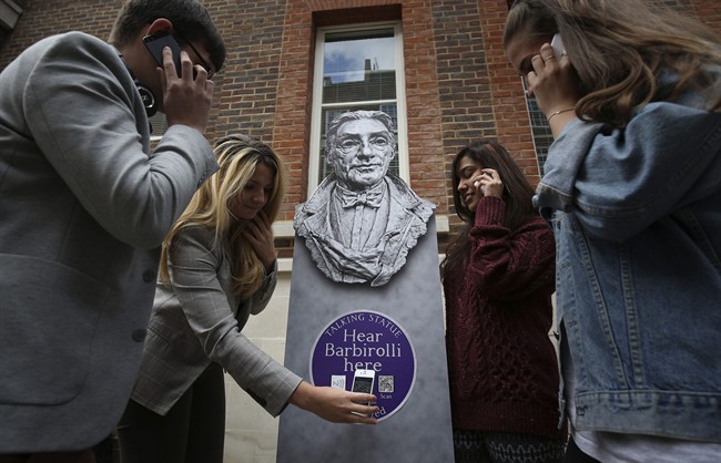 People listen to a talking statue on their phones at the launch of Talking Statues in central London, Tuesday Aug. 19, 2014. 