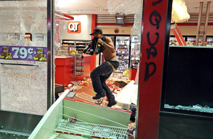 A man leaves a store on Sunday, Aug. 10, 2014, in Ferguson, Mo. A few thousand people crammed a suburban St. Louis street Sunday night at a vigil for unarmed 18-year-old Michael Brown shot and killed by a police officer, while afterward several car windows were smashed and stores were looted as people carried away armloads of goods as witnessed by an an Associated Press reporter.