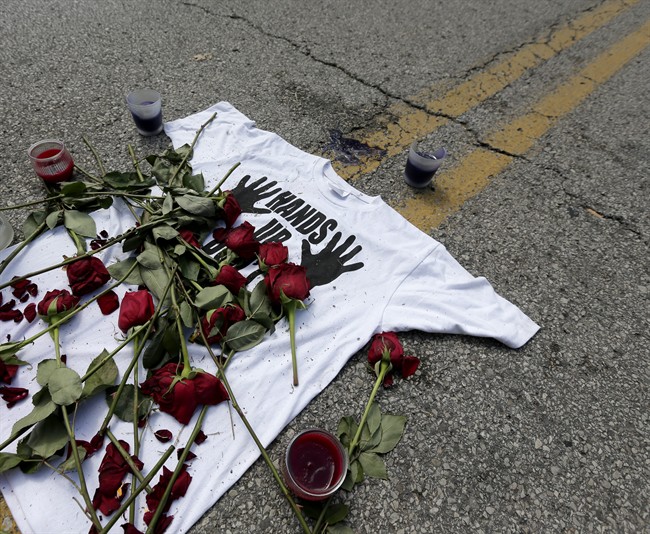A shirt reading "hands up don't shoot" is covered with roses Tuesday, Aug. 19, 2014, at the spot Michael Brown was killed by police Aug. 9 in Ferguson, Mo.