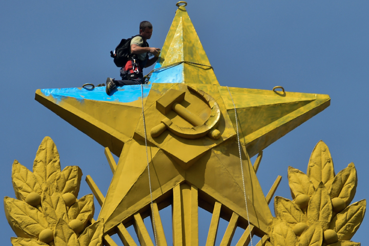 A worker climber repaints in yellow a blue star at the top of a Stalin-era skyscraper in Moscow, on August 20, 2014. This giant star was painted in yellow and blue, the Ukrainian national colors, by unknown people. 