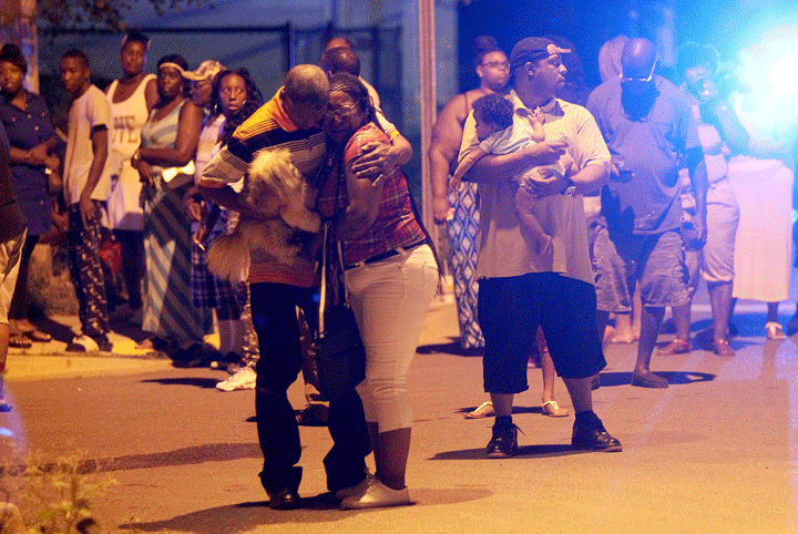 People grieve at the scene where New Orleans Police investigate a shooting in the Lower 9th Ward neighborhood of New Orleans, Sunday, Aug. 10, 2014.