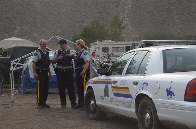 RCMP stand at the entrance to the camping area of the Boonstock Music and Art Festival in Penticton, B.C., where a 24-year-old woman from Leduc, Alberta died as the result of a drug overdose, early Saturday morning, Aug. 2, 2014. THE CANADIAN PRESS/Penticton Herald-James Miller.