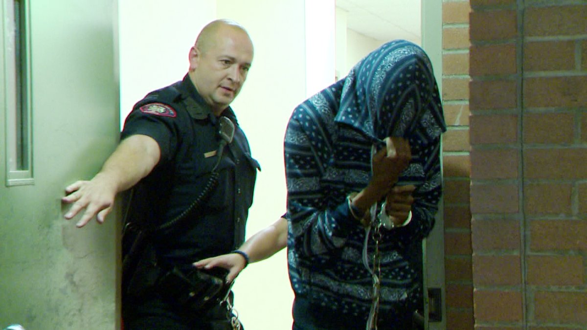 Officers escort Hussein Ibrahim out of the Calgary Police Service's arrest processing unit on Wednesday, August 28th, 2014. 
