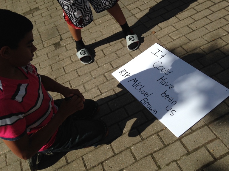 A boy finishes a poster saying "It could have been us".