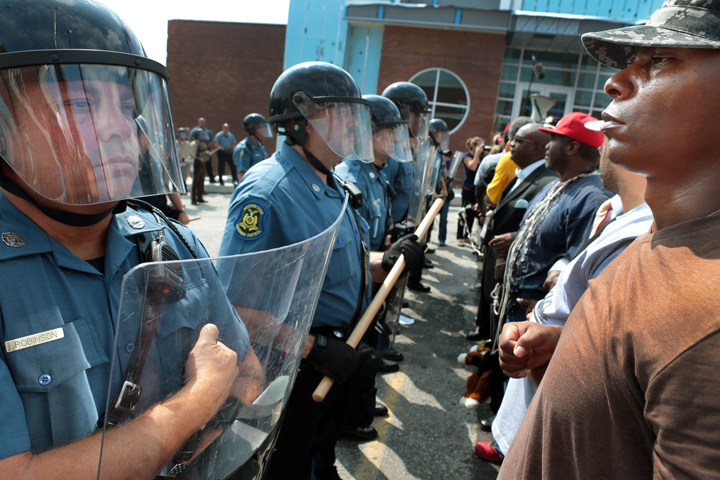 Protestor Boss Bastain of St. Louis locks arms with others as they confront Missouri State Highway Patrol troopers in front of the Ferguson police station on Monday, Aug. 11, 2014.  
