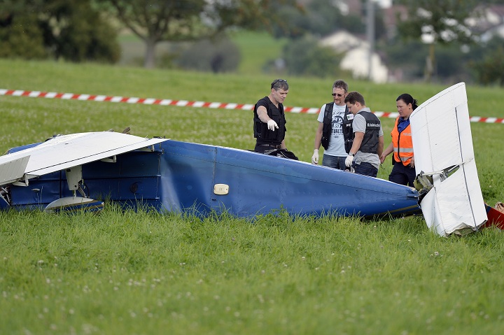 Police inspect the wreckage of a small plane that collided with another plane and crashed  during an  emergency landing  near Moerikon, Switzerland, Sunday Aug. 24, 2014. Police say two small planes have  collided over northeastern Switzerland, injuring seven people.