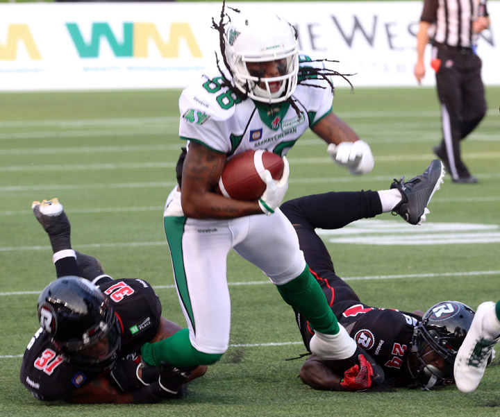 Saskatchewan Roughriders' Taj Smith(88) has his feet grabbed by Ottawa Redblacks' Jasper Simmons (31) Jarrel Williams (24) during CFL football action in Ottawa, Saturday August 2, 2014.
