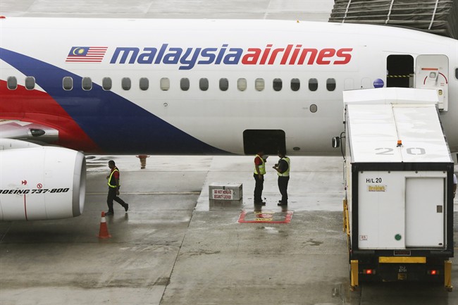 In this May 27, 2014 file photo, ground crew stand near a Malaysia Airlines aircraft on the tarmac at the Kuala Lumpur International Airport (KLIA) in Sepang, Malaysia. 