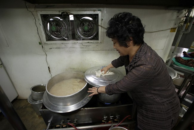 In this photo taken on Tuesday, Aug. 12, 2014, a chef and owner Oh Keum-il of Daegyo, the dog meat restaurant, shows how to cook for dog meat at her restaurant in Seoul, South Korea. 