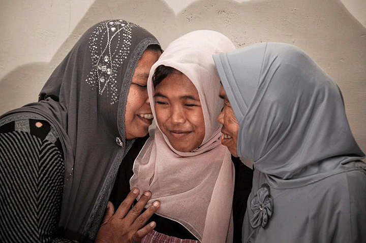 Jamaliah (left) gives a hug to Raudhatul Jannah (centre), with Raudhatul's grandmother (right), after being reunited in Meulaboh, Aceh.