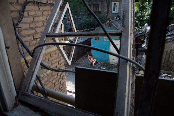 A local resident walks past her damaged house after shelling in Petrovsky district in the city of Donetsk, eastern Ukraine Tuesday, Aug. 5, 2014. 