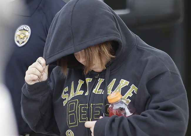 In this photo taken on Tuesday, Aug. 26, 2014, Alicia Marie Englert shields her face as she is escorted by police from a home in Kearns, Utah.