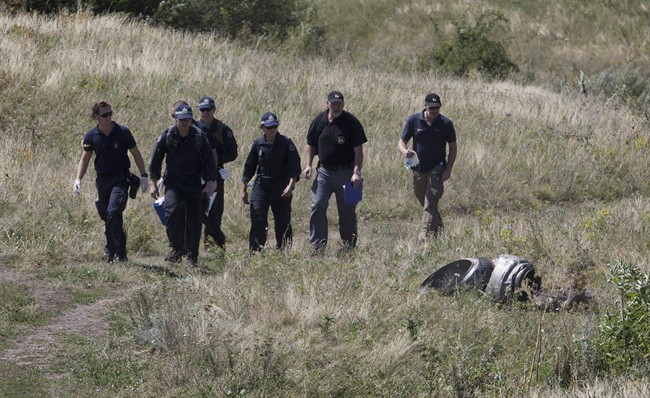 Australian experts examine the area of the Malaysia Airlines Flight 17 plane crash in the village of Hrabove, Donetsk region, eastern Ukraine Friday, Aug. 1, 2014. (AP Photo/Dmitry Lovetsky).
