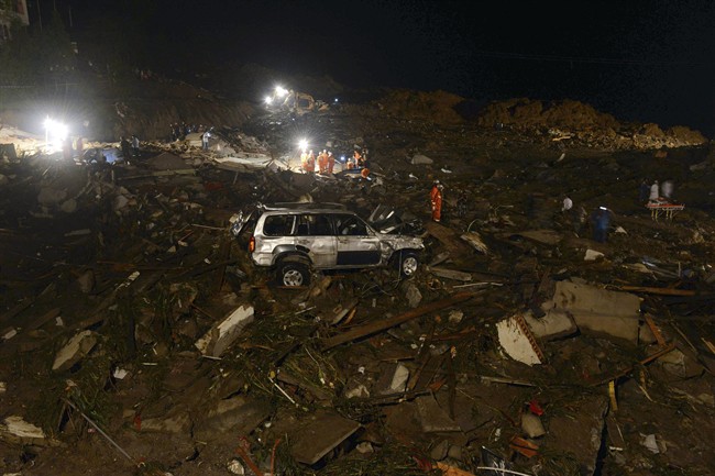 Rescue workers search for victims in the aftermath of a landslide that hit Yingping village in Fuquan city in southwest China's Guizhou province Thursday Aug. 28, 2014. Six people died and 21 remained missing Thursday after a landslide hit a village in southwestern China, according to Chinese state media.