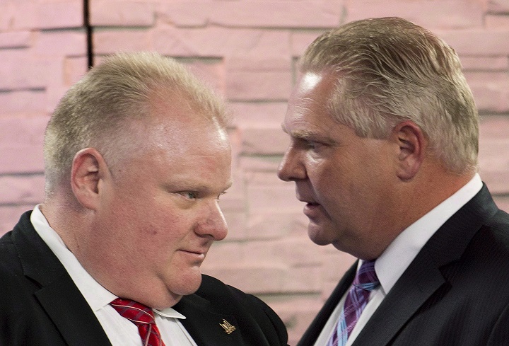 Mayor Rob Ford, left, listens to his brother and campaign manager Doug Ford, right, during a commercial break as Rob Ford takes part in a live television mayoral debate in Toronto on Wednesday, March 26, 2014. 