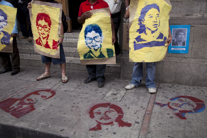 In this Friday, May 16, 2014 photo, demonstrators outside the National Congress building in Guatemala City hold posters of people disappeared in the 1980s as they protest a resolution that denies there was any attempt to commit genocide during the bloody 36-year civil war.
