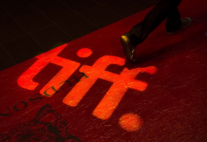A man walks on a red carpet displaying a sign for the Toronto International Film Festival at the TIFF Bell Lightbox in Toronto on Wednesday, September 3, 2014. 