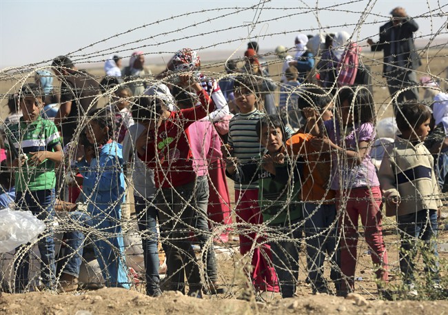 Several hundred Syrian refugees wait to cross into Turkey at the border in Suruc, Turkey, in September 2014.