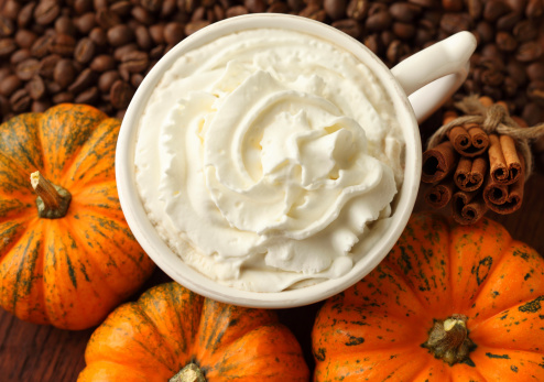 Whipped cream floats on a pumpkin-spiced coffee.