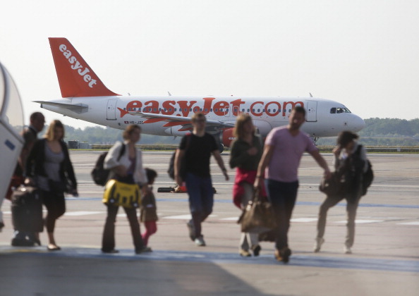 Passengers walk across the tarmac as a EasyJet Plc aircraft stands beyond at Schoenefeld airport, operated by Flughafen Berlin-Schoenefeld GmbH, in Berlin, Germany, on Thursday, July 17, 2014. 