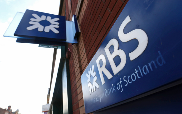 An RBS logo sits on a sign above the entrance to Royal Bank of Scotland Group Plc (RBS) bank branch in Burton-upon-Trent, U.K., on Wednesday, Aug. 27, 2014. 