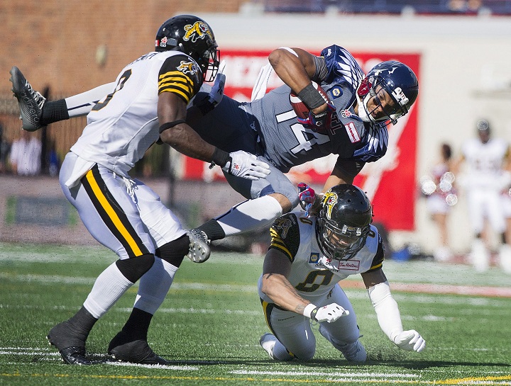 Montreal Alouettes' Brandon London (14) is tackled by Hamilton Tiger-Cats Rico Murray and Brandon Stewart during second half CFL football action in Montreal, Sunday, September 7, 2014.