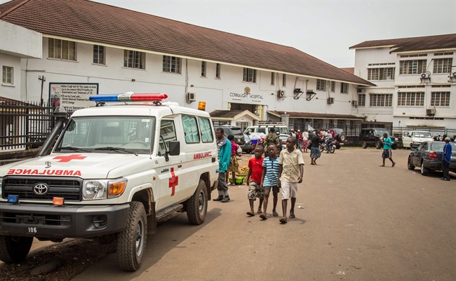 In this photo taken on Sunday, Sept. 14, 2014, boys, center, walk past an ambulance, left, equipped to carry Ebola patients, outside the Connaught Hospital in Freetown, Sierra Leone. (AP Photo/ Michael Duff).