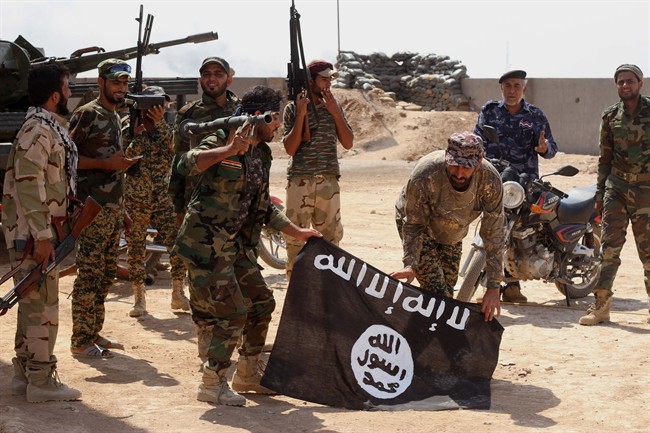 Iraqi security forces hold a flag of the Islamic State group they captured during an operation outside Amirli, some 105 miles (170 kilometers) north of Baghdad, Iraq, Monday, Sept. 1, 2014. 