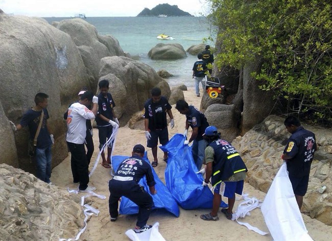 Thai officers work near the bodies of two British tourists Monday, Sept. 15, 2014 on a beach in Surat Thani province, southern Thailand. 