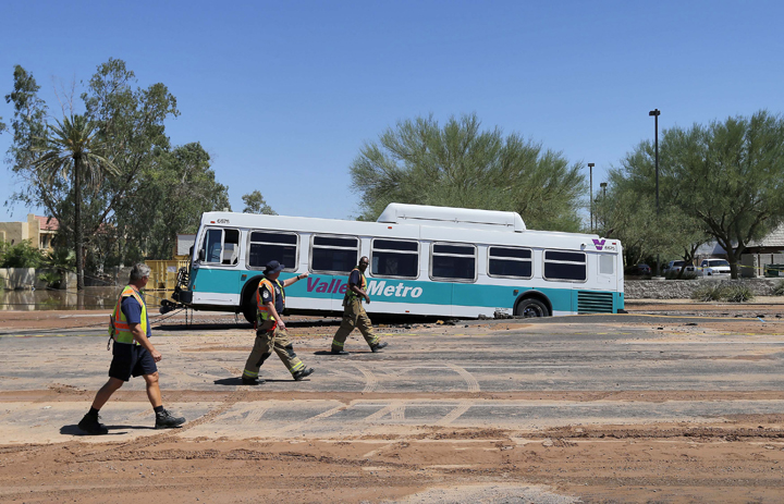 A valley metro bus sits mired in a collapsed, muddy street after a water main break flooded the area, Wednesday, Sept. 3, 2014 in Tempe, Ariz. 