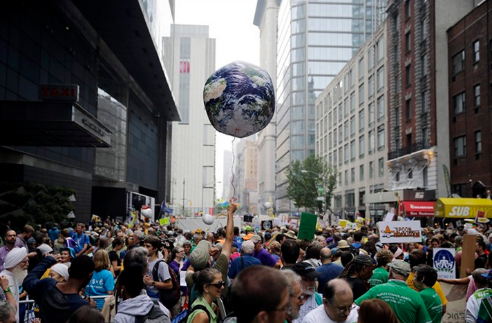 A man throws an earth balloon into the air as people fill 58th Street between 8th and 9th Avenue before a global warming march in New York Sunday, Sept. 21, 2014. (AP Photo/Mel Evans).