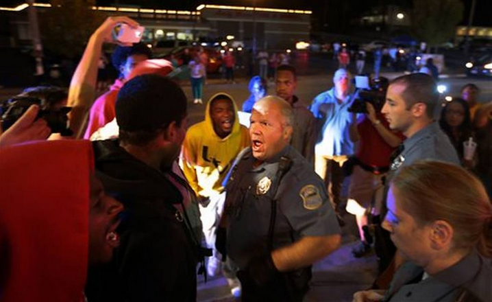 Protesters exchange words with a Ferguson police officer who was moving them off the street in front of the Ferguson Police Department, as they called for the resignation of Chief Tom Jackson on Thursday, Sept. 25, 2014.
