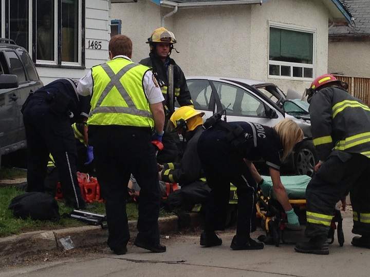 Firefighters tend to a victim of a crash on Pacific Avenue W. in Winnipeg on Wednesday.