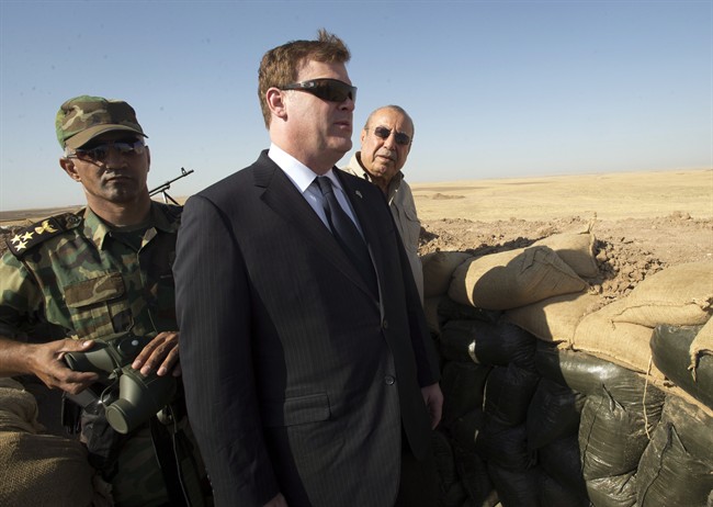 Canadian Foreign Affairs Minister John Baird, centre, and Iraqi Deputy Minister Rowsch Nouri Sharways look at ISIS positions from a front line bunker Thursday, Sept. 4, 2014 in Kalak, Iraq.