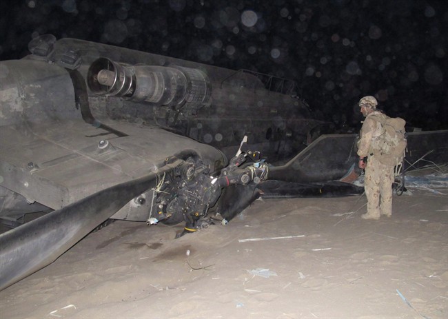 A Canadian soldier examines the wreckage of a Chinook minutes after it crashed on landing under moonlight in a remote part of Panjwaii district in southern Afghanistan on Monday, May 16, 2011. 