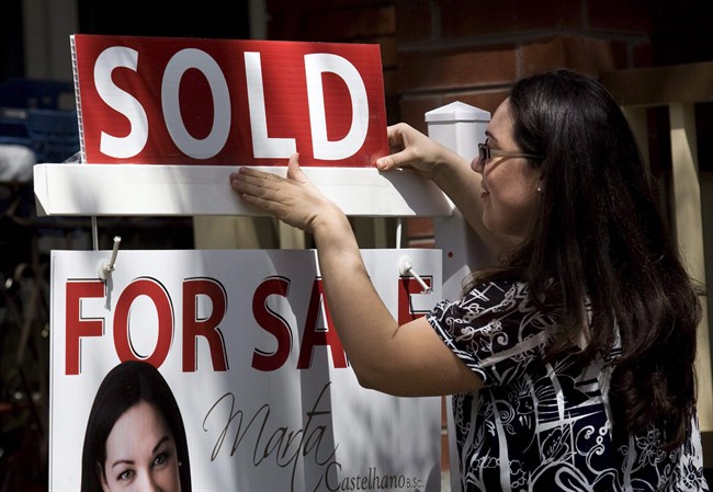A real estate agent puts up a "sold" sign in front of a house in Toronto on April 20, 2010.