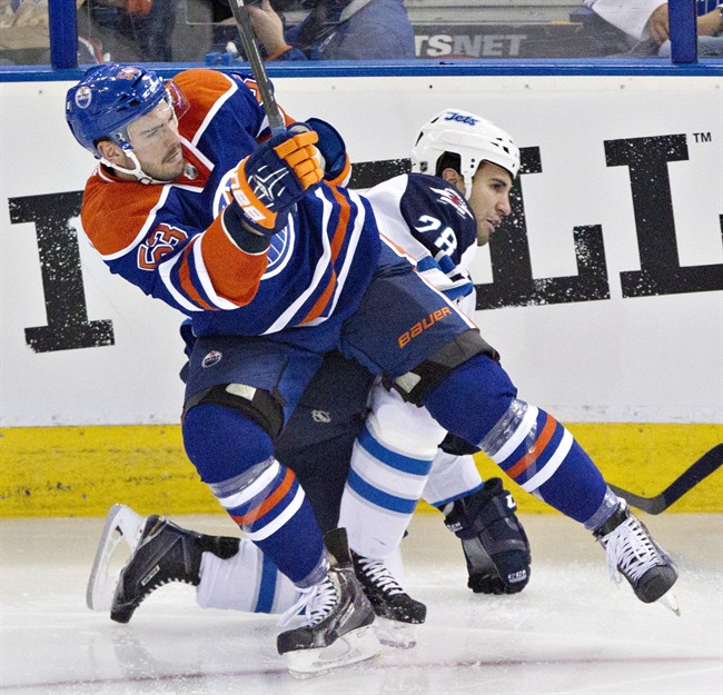 Winnipeg Jets Patrice Cormier is checked by Edmonton Oilers Mitchell Moroz during a game in Edmonton on September 29, 2014.